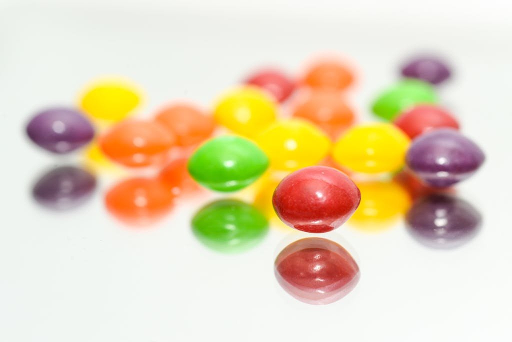 A vibrant close-up of colorful Skittles reflecting on a glossy surface.